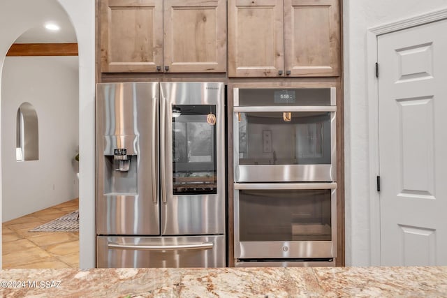 kitchen featuring light tile patterned flooring, light stone countertops, stainless steel appliances, and light brown cabinetry