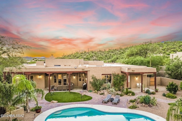 back house at dusk featuring a patio