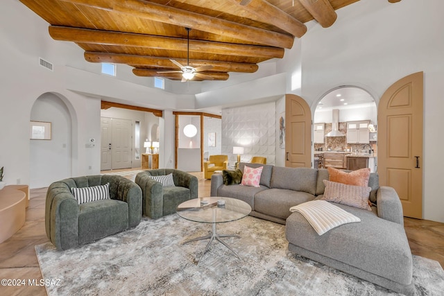 living room with wooden ceiling, a high ceiling, sink, ceiling fan, and beamed ceiling