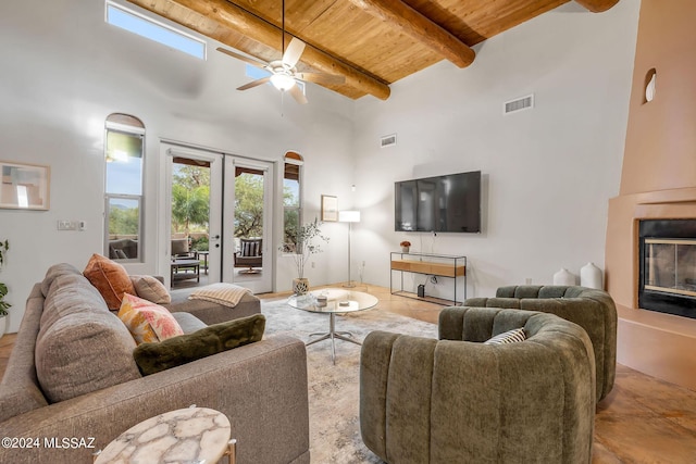 living room with beam ceiling, a fireplace, wooden ceiling, and a high ceiling