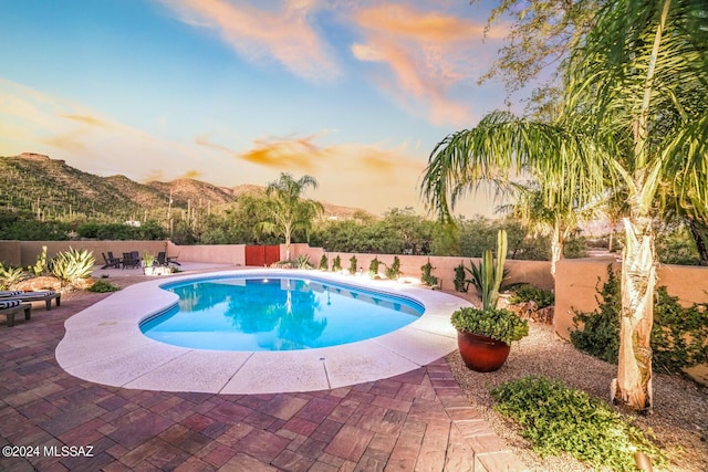 pool at dusk with a mountain view and a patio