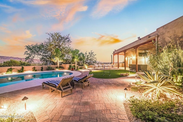 pool at dusk featuring a patio