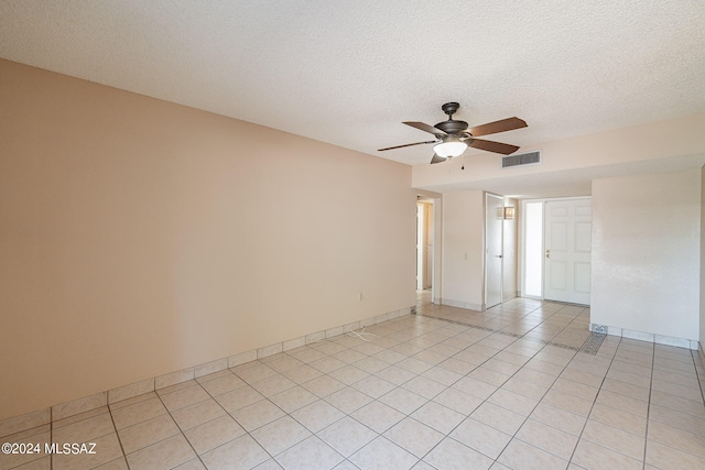 spare room with a textured ceiling, light tile patterned floors, and ceiling fan