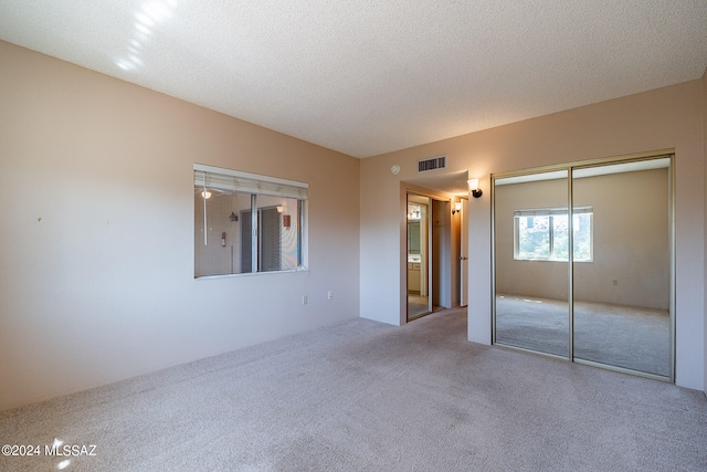 unfurnished bedroom featuring a textured ceiling, carpet flooring, and a closet