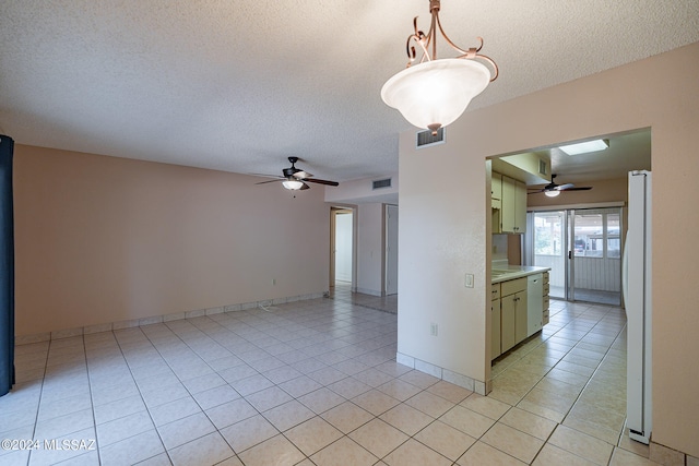 tiled empty room featuring a textured ceiling and ceiling fan