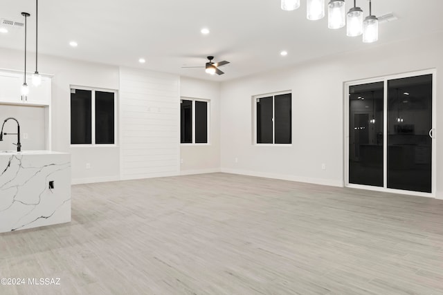 empty room with ceiling fan, light wood-type flooring, and sink