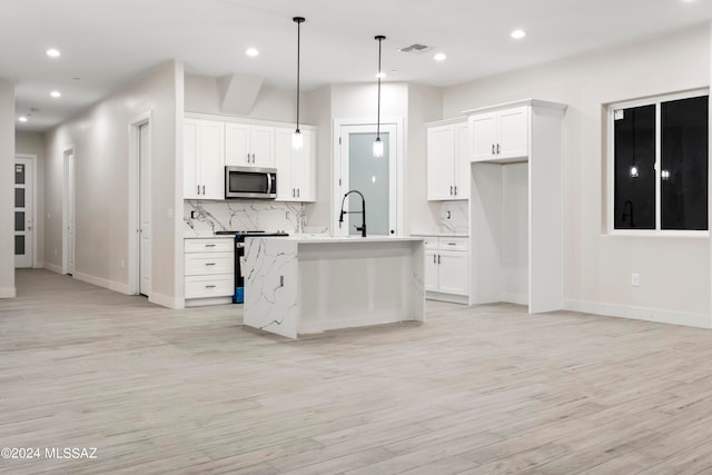 kitchen featuring light hardwood / wood-style floors, a kitchen island with sink, and white cabinetry