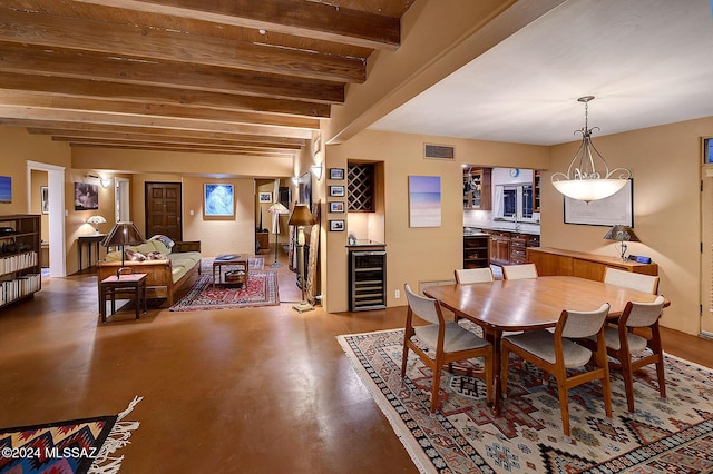 dining area with beamed ceiling, bar area, beverage cooler, and concrete flooring