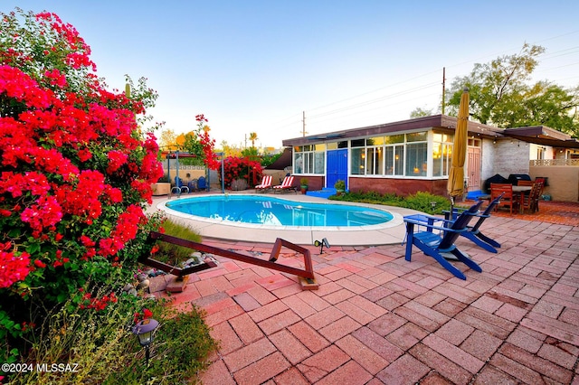 view of pool with a sunroom and a patio