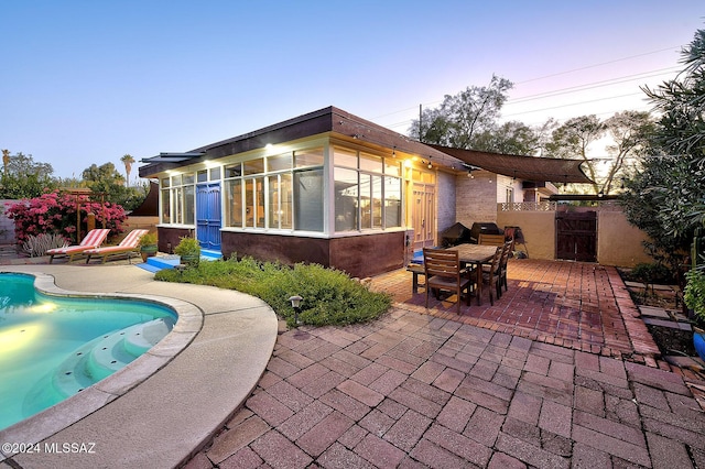 back house at dusk featuring a patio area