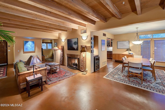 living room featuring wine cooler, a wealth of natural light, concrete floors, and beamed ceiling