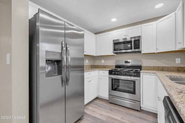 kitchen featuring sink, white cabinetry, light stone counters, light wood-type flooring, and stainless steel appliances