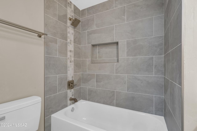 bathroom featuring tiled shower / bath combo and toilet