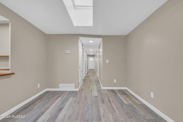 interior space with a skylight and light hardwood / wood-style flooring