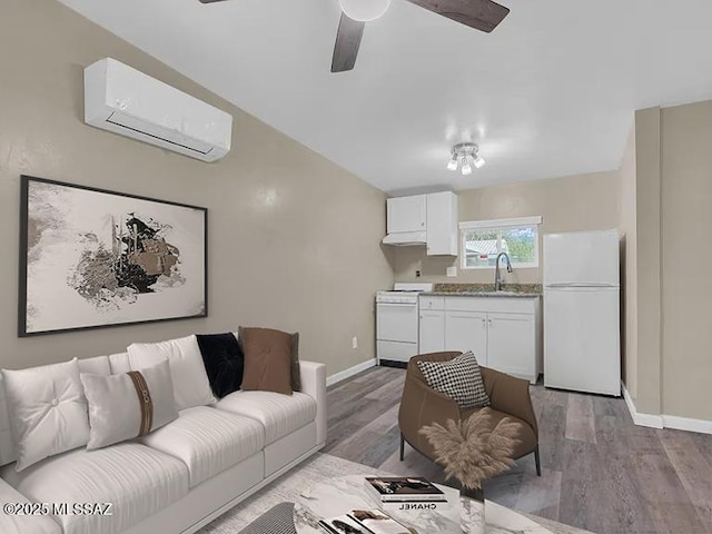 living room featuring ceiling fan, a wall mounted air conditioner, sink, and light hardwood / wood-style flooring