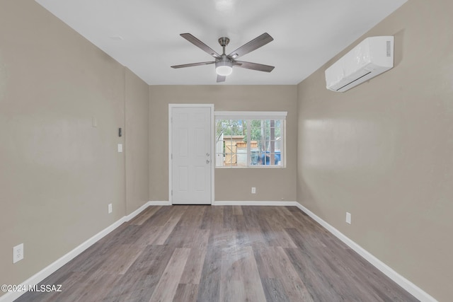 empty room with ceiling fan, a wall unit AC, and light hardwood / wood-style flooring