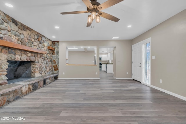 unfurnished living room with ceiling fan, wood-type flooring, and a fireplace