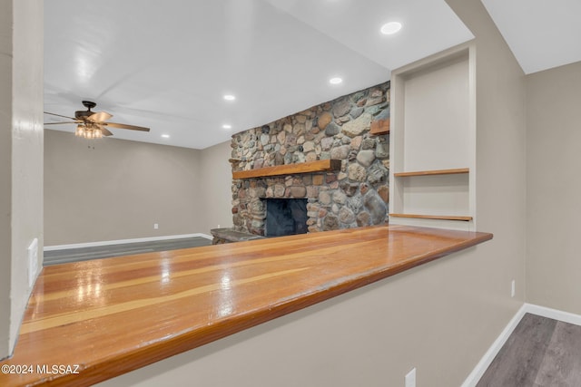 unfurnished living room with a stone fireplace, hardwood / wood-style floors, and ceiling fan