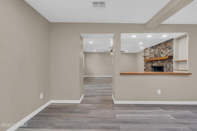 interior space featuring hardwood / wood-style flooring, ceiling fan, and a stone fireplace