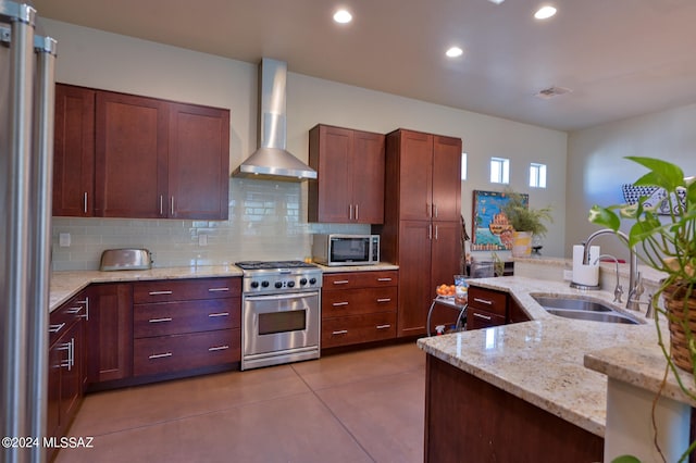 kitchen featuring stainless steel appliances, tasteful backsplash, light stone countertops, wall chimney exhaust hood, and sink