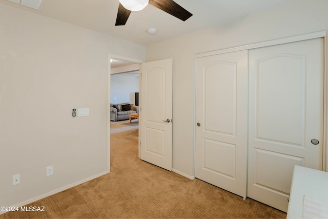 unfurnished bedroom with ceiling fan, light carpet, and a closet