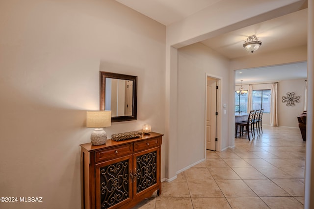 hallway with light tile patterned floors and a chandelier