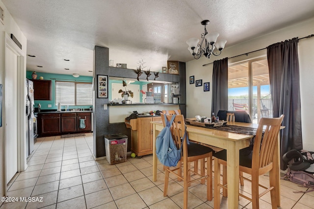 dining room with light tile floors, plenty of natural light, a textured ceiling, and a chandelier