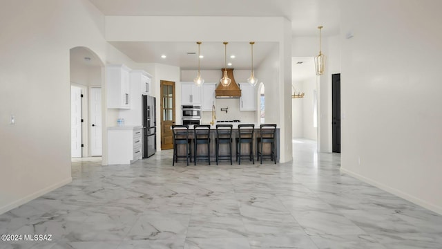 kitchen with light tile floors, white cabinets, hanging light fixtures, and a breakfast bar area