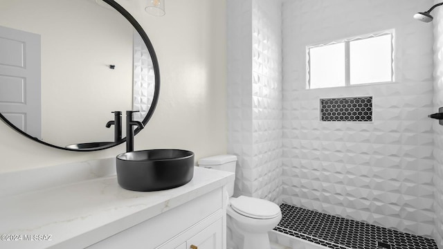 bathroom featuring oversized vanity, toilet, and a tile shower