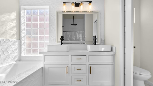 bathroom featuring vanity with extensive cabinet space, toilet, and tiled bath