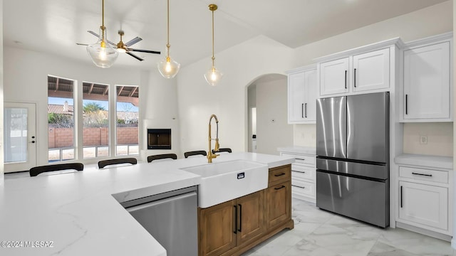 kitchen with appliances with stainless steel finishes, white cabinetry, light tile floors, ceiling fan, and sink