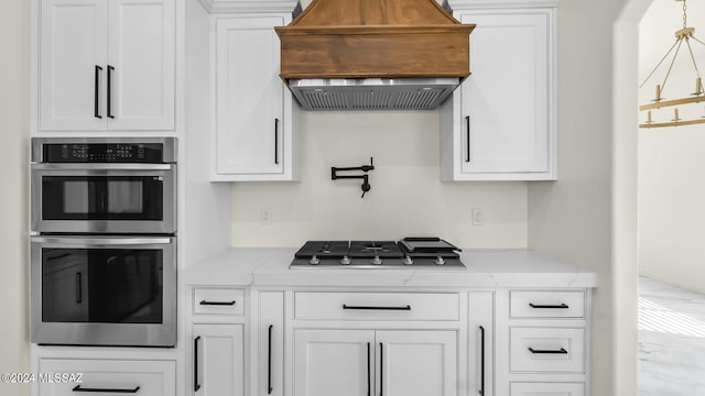 kitchen with decorative light fixtures, white cabinetry, custom range hood, and stainless steel appliances