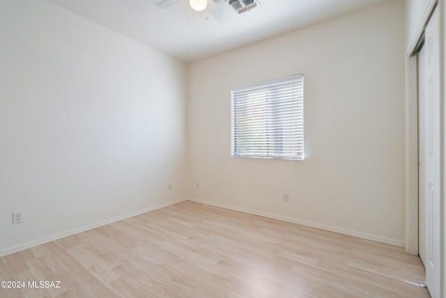 unfurnished bedroom featuring ceiling fan, light hardwood / wood-style floors, and a closet