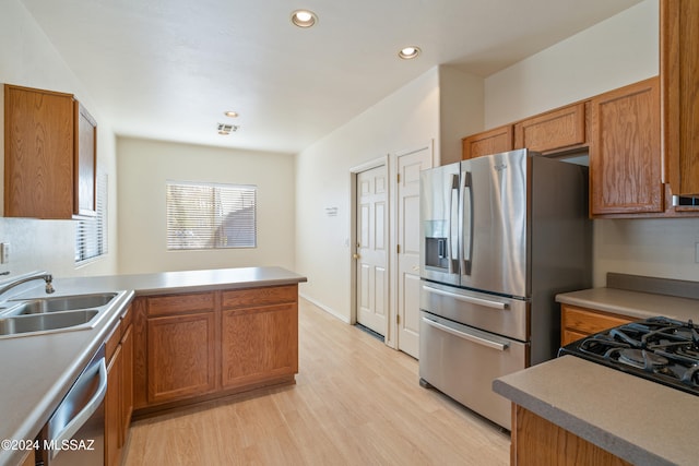 kitchen featuring kitchen peninsula, appliances with stainless steel finishes, light hardwood / wood-style flooring, and sink