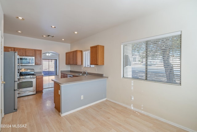 kitchen with plenty of natural light, light wood-type flooring, kitchen peninsula, and stainless steel appliances