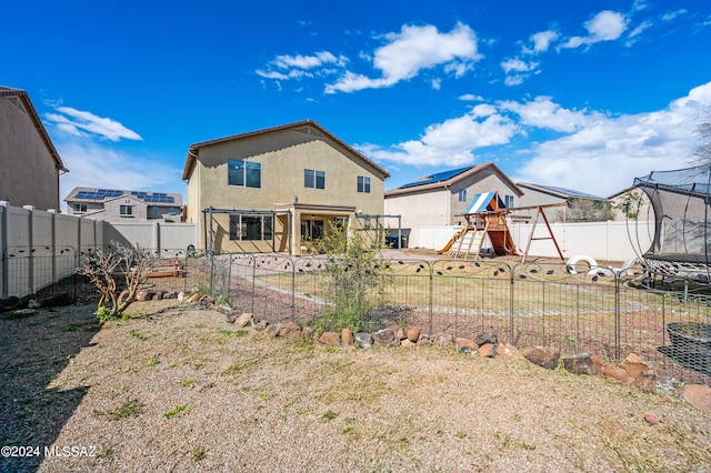 rear view of house with a playground and a trampoline