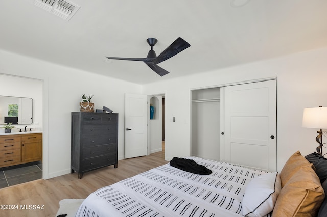 bedroom with ceiling fan, a closet, ensuite bathroom, and light hardwood / wood-style floors