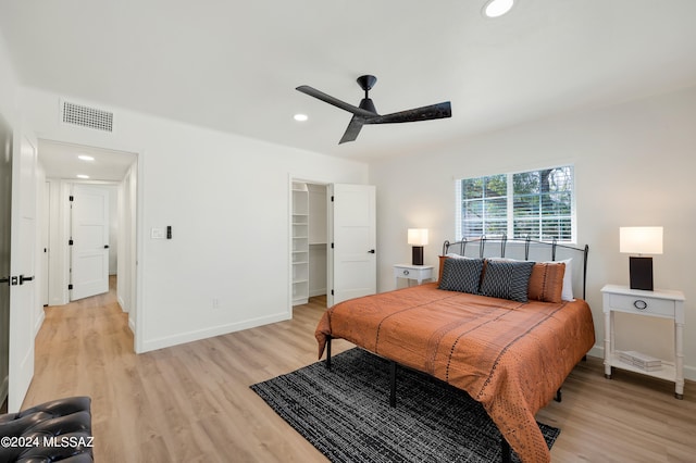 bedroom featuring a closet, ceiling fan, a walk in closet, and light hardwood / wood-style flooring