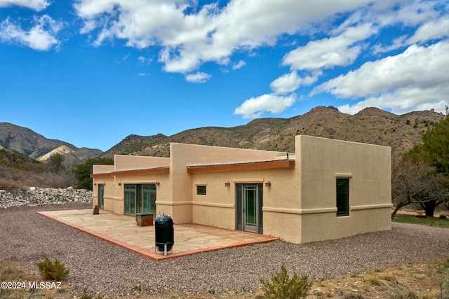 back of property featuring a mountain view and a patio area