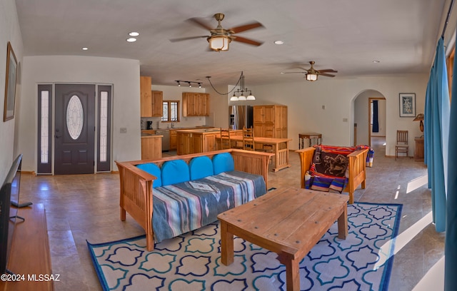 tiled living room with ceiling fan with notable chandelier and track lighting