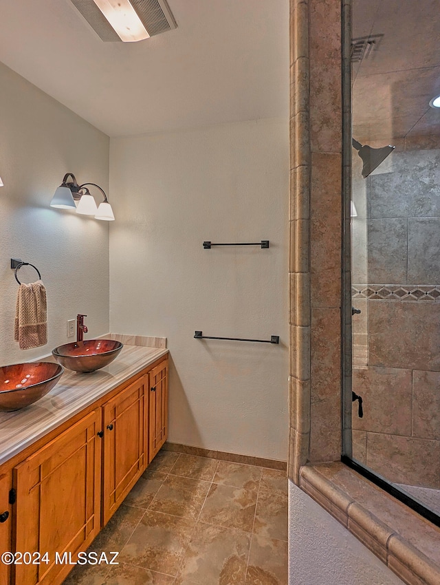 bathroom with a shower with shower door, tile floors, and vanity