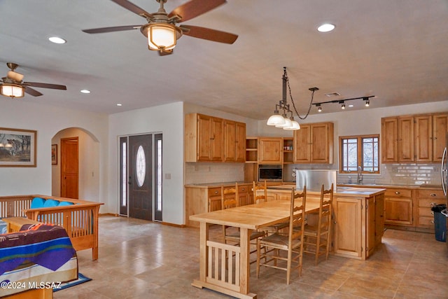 kitchen with pendant lighting, a center island, ceiling fan, backsplash, and sink