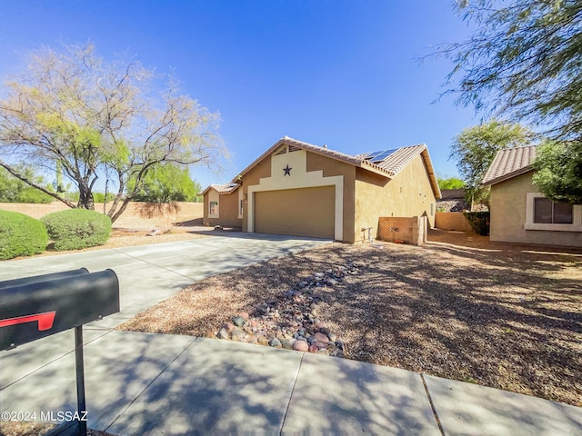 exterior space featuring a tile roof, stucco siding, roof mounted solar panels, fence, and driveway