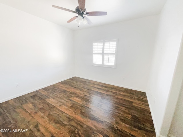 empty room featuring dark wood-style flooring, ceiling fan, and baseboards