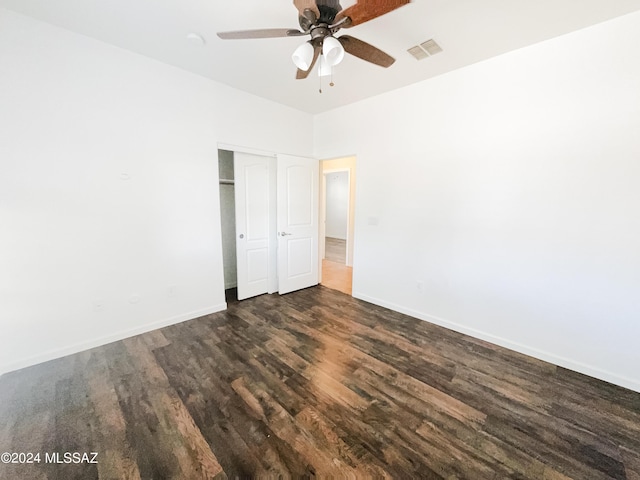 unfurnished bedroom with a closet, visible vents, ceiling fan, wood finished floors, and baseboards