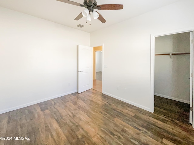 unfurnished bedroom featuring baseboards, visible vents, ceiling fan, wood finished floors, and a closet