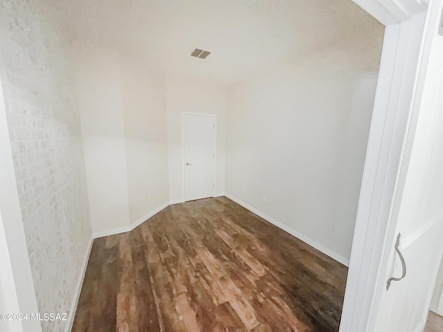 spare room with wood finished floors, visible vents, and baseboards