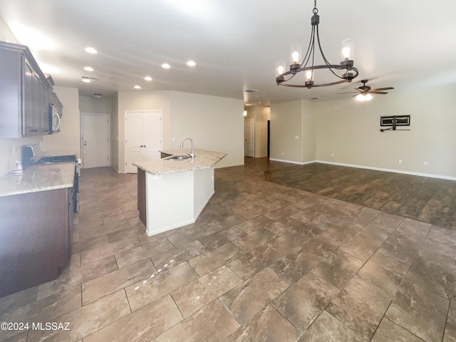 kitchen with a center island with sink, light stone countertops, stainless steel appliances, a sink, and recessed lighting