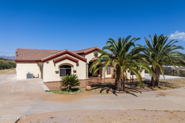 mediterranean / spanish house with central air condition unit, stucco siding, and a tile roof