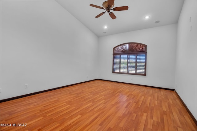 spare room featuring ceiling fan, light wood-type flooring, and lofted ceiling